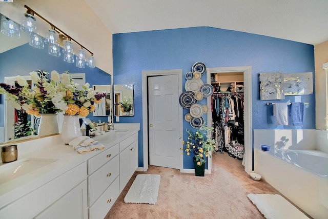 bathroom featuring lofted ceiling, vanity, and a bathing tub