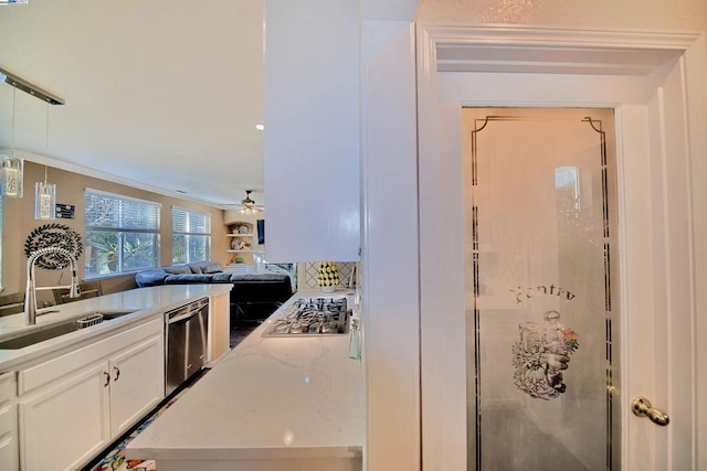 kitchen with sink, ceiling fan, appliances with stainless steel finishes, white cabinetry, and light stone counters