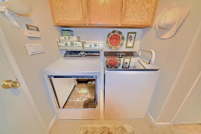 clothes washing area featuring cabinets, separate washer and dryer, and light tile patterned floors