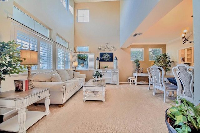 carpeted living room featuring an inviting chandelier, a high ceiling, and a wealth of natural light