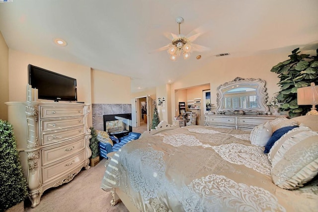 carpeted bedroom with a tile fireplace, vaulted ceiling, and ceiling fan