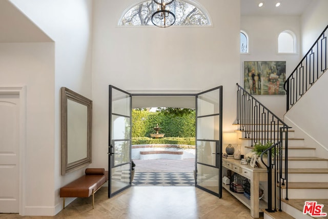 foyer entrance featuring a healthy amount of sunlight, a chandelier, and a high ceiling