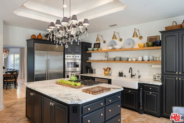 kitchen with a kitchen island, a raised ceiling, sink, light parquet floors, and stainless steel appliances