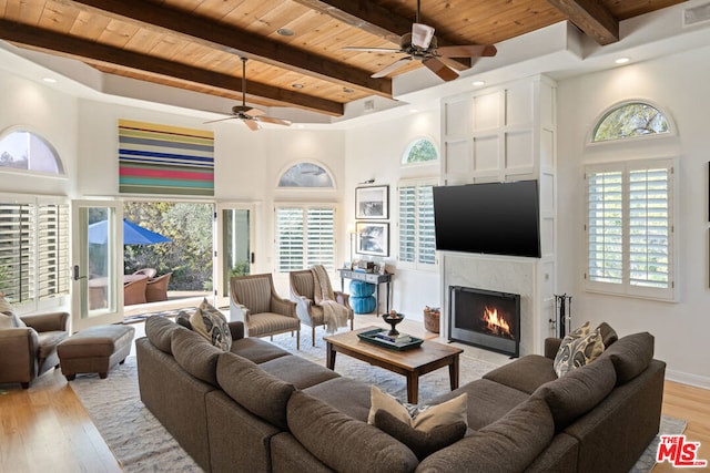 living room featuring beam ceiling, a fireplace, and wooden ceiling