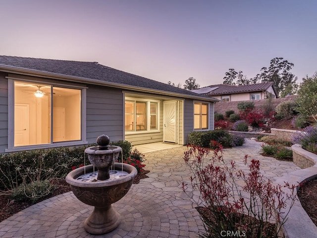 back house at dusk featuring a patio area