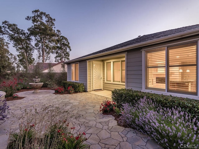 exterior entry at dusk featuring a patio