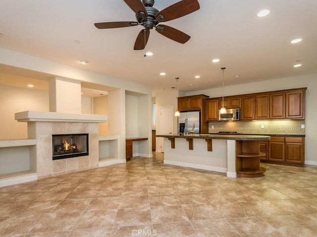 kitchen with a breakfast bar area, tasteful backsplash, decorative light fixtures, a center island with sink, and appliances with stainless steel finishes