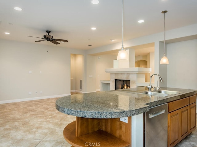 kitchen with a premium fireplace, sink, pendant lighting, and a kitchen island with sink