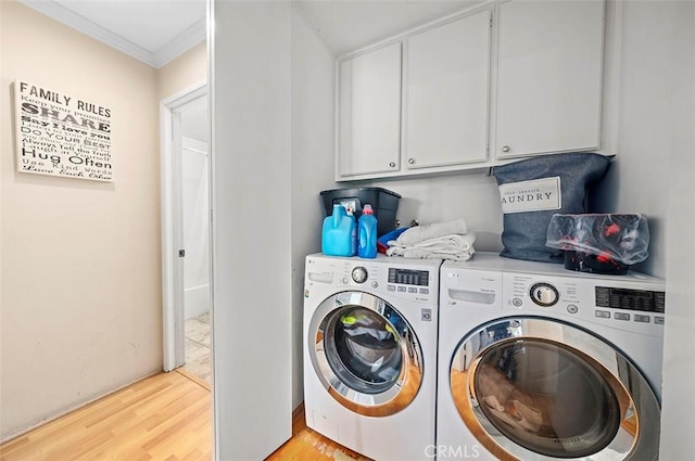 laundry area with cabinets, ornamental molding, light hardwood / wood-style floors, and washing machine and dryer