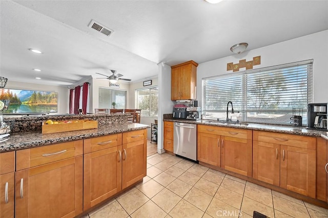 kitchen featuring sink, light tile patterned floors, dishwasher, ceiling fan, and dark stone counters