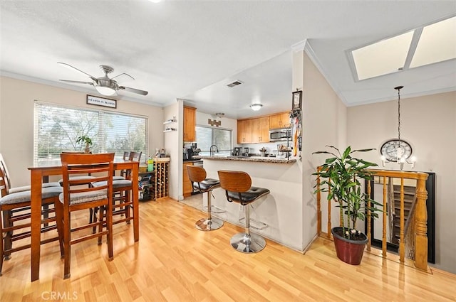 kitchen featuring crown molding, ceiling fan with notable chandelier, kitchen peninsula, and light hardwood / wood-style floors