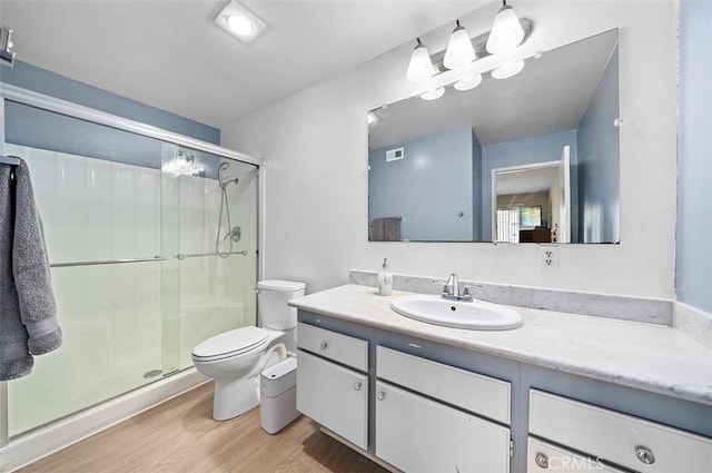 bathroom featuring a shower with door, vanity, hardwood / wood-style floors, and toilet