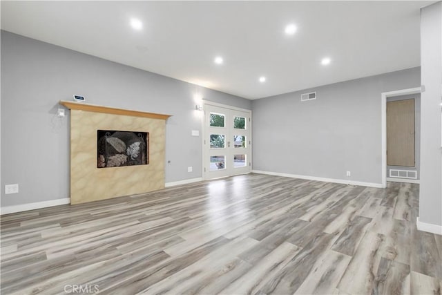 unfurnished living room with light wood-type flooring and french doors