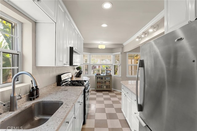 kitchen with sink, stainless steel appliances, white cabinets, and light stone countertops