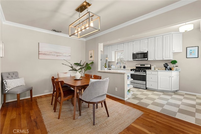 dining room with crown molding, sink, and light wood-type flooring