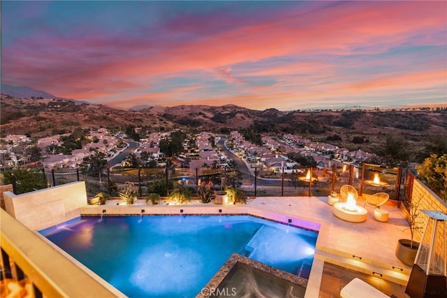 pool at dusk featuring a mountain view and a fire pit