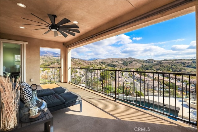 balcony featuring a mountain view and ceiling fan