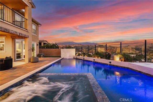 pool at dusk with an in ground hot tub, a mountain view, and cooling unit