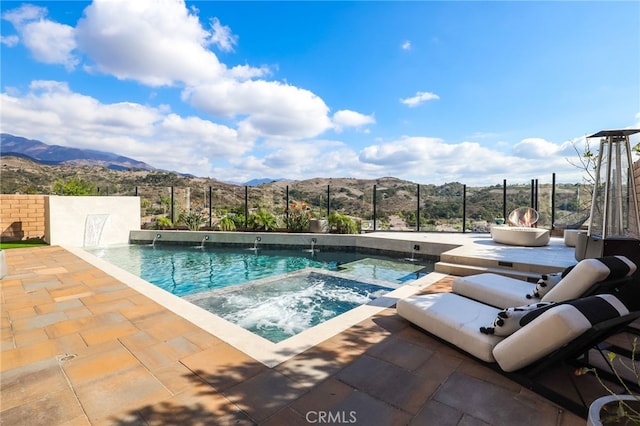 view of pool featuring a mountain view, a patio area, pool water feature, and an in ground hot tub