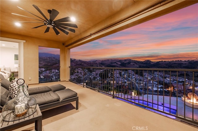 balcony at dusk with ceiling fan and a mountain view