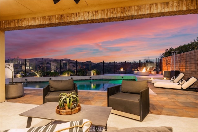 pool at dusk featuring a patio area and ceiling fan