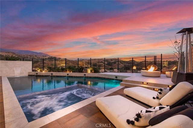 view of pool featuring fence, a mountain view, and a pool with connected hot tub