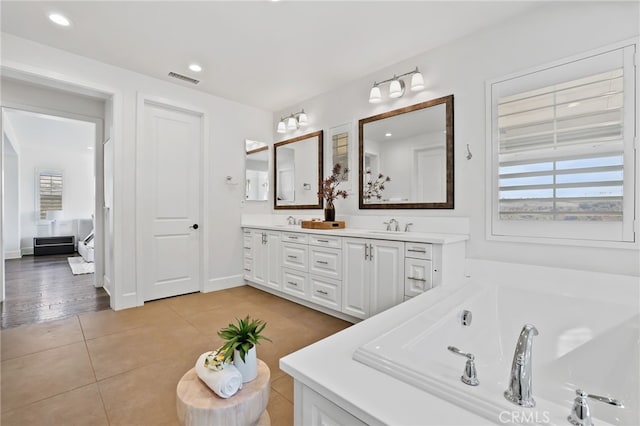 bathroom with a tub to relax in, vanity, and tile patterned flooring