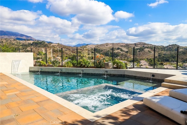 view of swimming pool with a mountain view, pool water feature, and an in ground hot tub