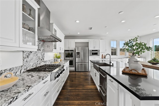 kitchen with wall chimney exhaust hood, tasteful backsplash, dark hardwood / wood-style flooring, stainless steel appliances, and white cabinets