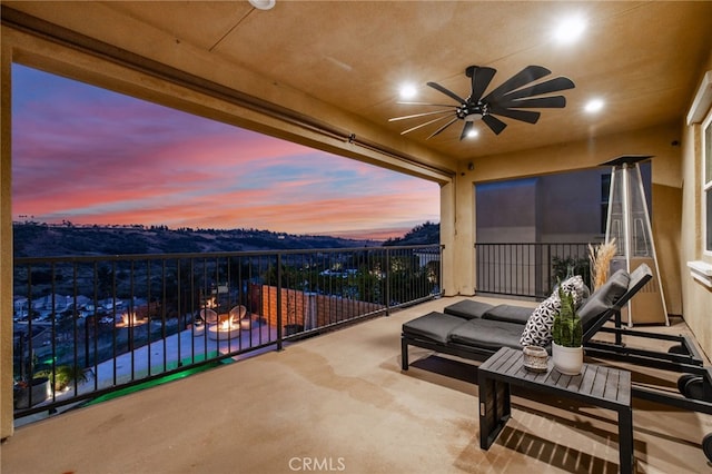 patio terrace at dusk featuring ceiling fan and a fire pit