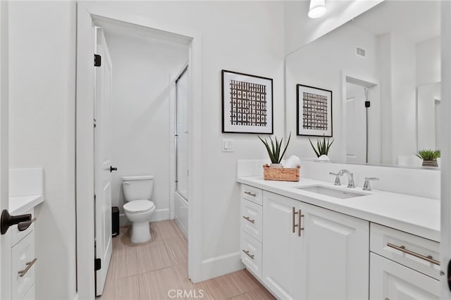 full bathroom featuring vanity, bath / shower combo with glass door, and toilet