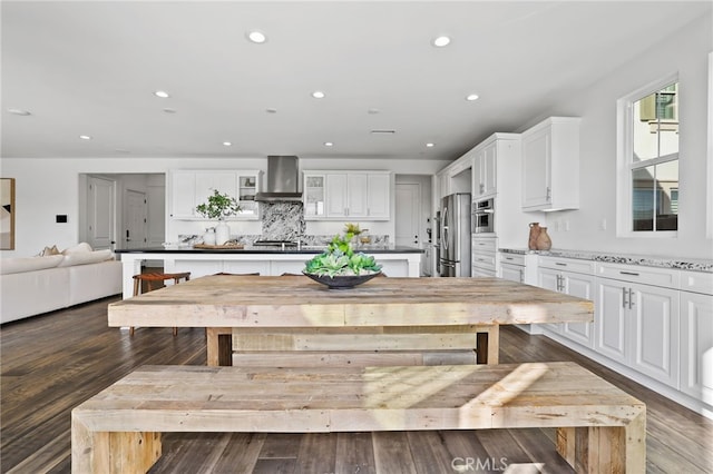 kitchen featuring white cabinets, stainless steel appliances, and wall chimney exhaust hood