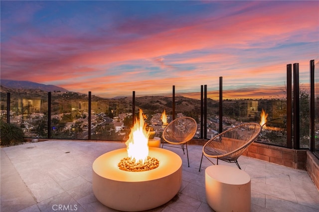 patio terrace at dusk featuring a mountain view and an outdoor fire pit