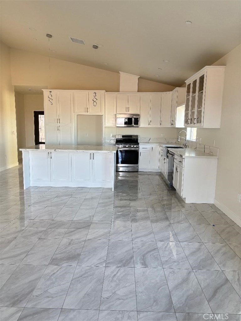 kitchen with white cabinetry, high vaulted ceiling, appliances with stainless steel finishes, and sink