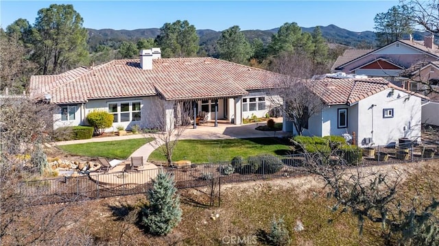 back of property featuring a yard, a mountain view, and a patio area