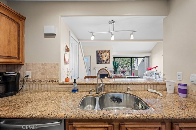 kitchen featuring light stone counters, sink, backsplash, and dishwasher