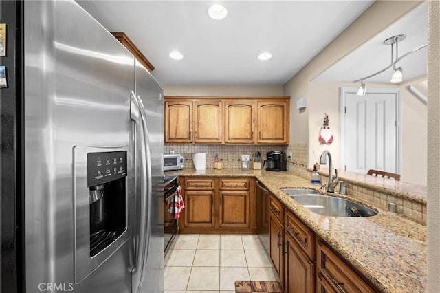 kitchen with sink, stainless steel appliances, light stone counters, tasteful backsplash, and light tile patterned flooring