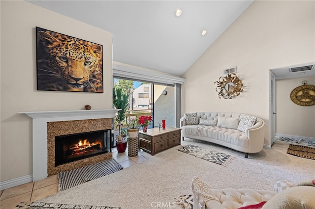 carpeted living room featuring a tiled fireplace and high vaulted ceiling