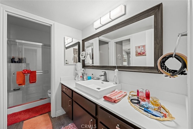 bathroom featuring vanity, hardwood / wood-style flooring, toilet, and walk in shower