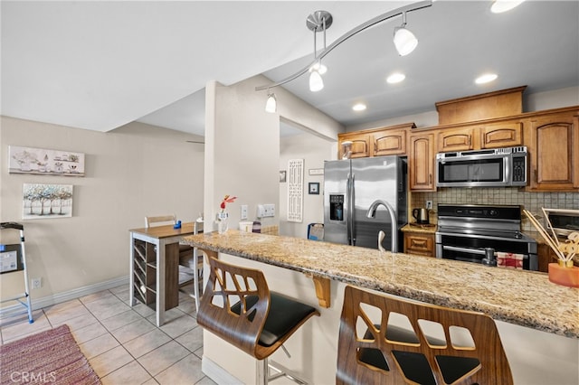 kitchen with light stone counters, backsplash, pendant lighting, and appliances with stainless steel finishes