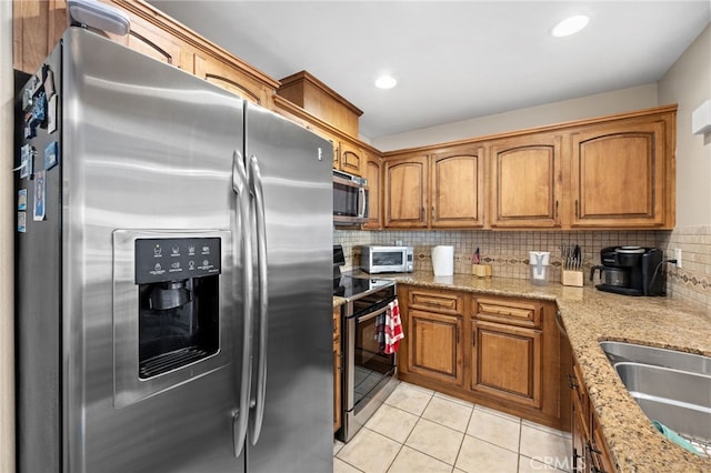 kitchen featuring tasteful backsplash, stainless steel appliances, light stone countertops, and light tile patterned floors