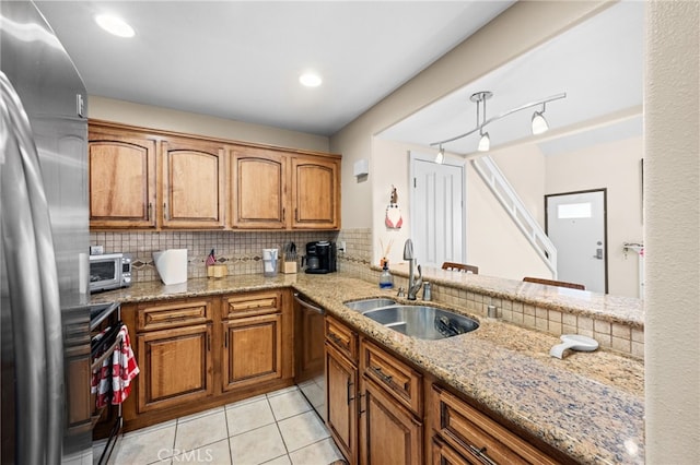 kitchen with tasteful backsplash, appliances with stainless steel finishes, sink, and light stone counters