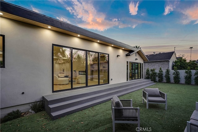 back house at dusk with a lawn