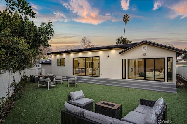 back house at dusk with a yard, an outdoor hangout area, and a patio