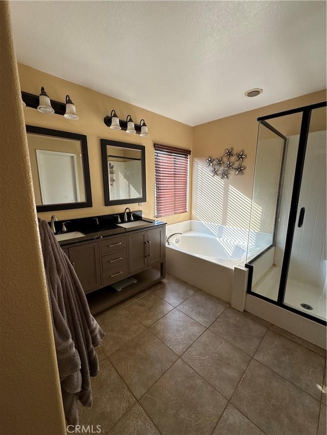 bathroom featuring double vanity, a garden tub, a textured ceiling, a stall shower, and a sink