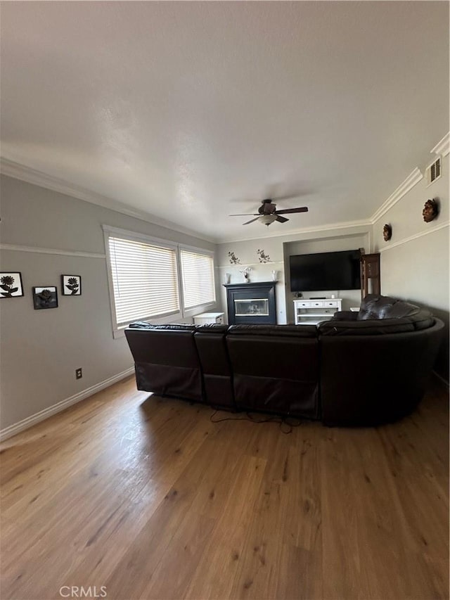 living room featuring ornamental molding, ceiling fan, and light wood-type flooring