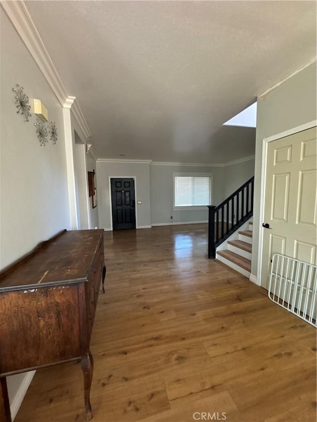 interior space featuring crown molding, baseboards, stairs, and wood finished floors