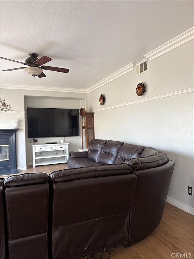 living room with hardwood / wood-style flooring, crown molding, and ceiling fan