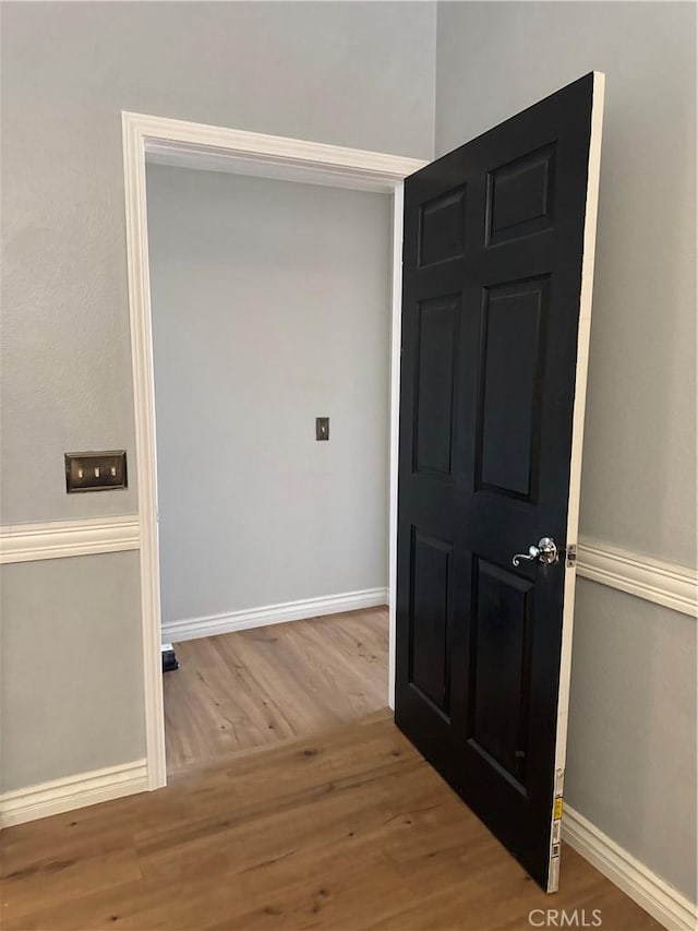 hall with baseboards and wood finished floors