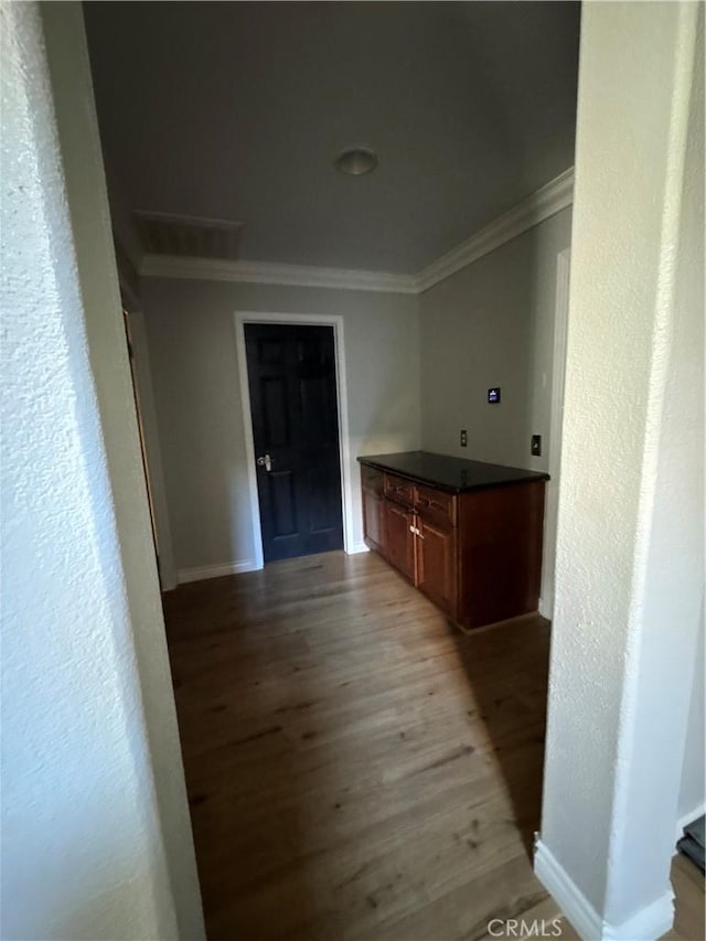 hallway with crown molding, light wood-style flooring, and baseboards